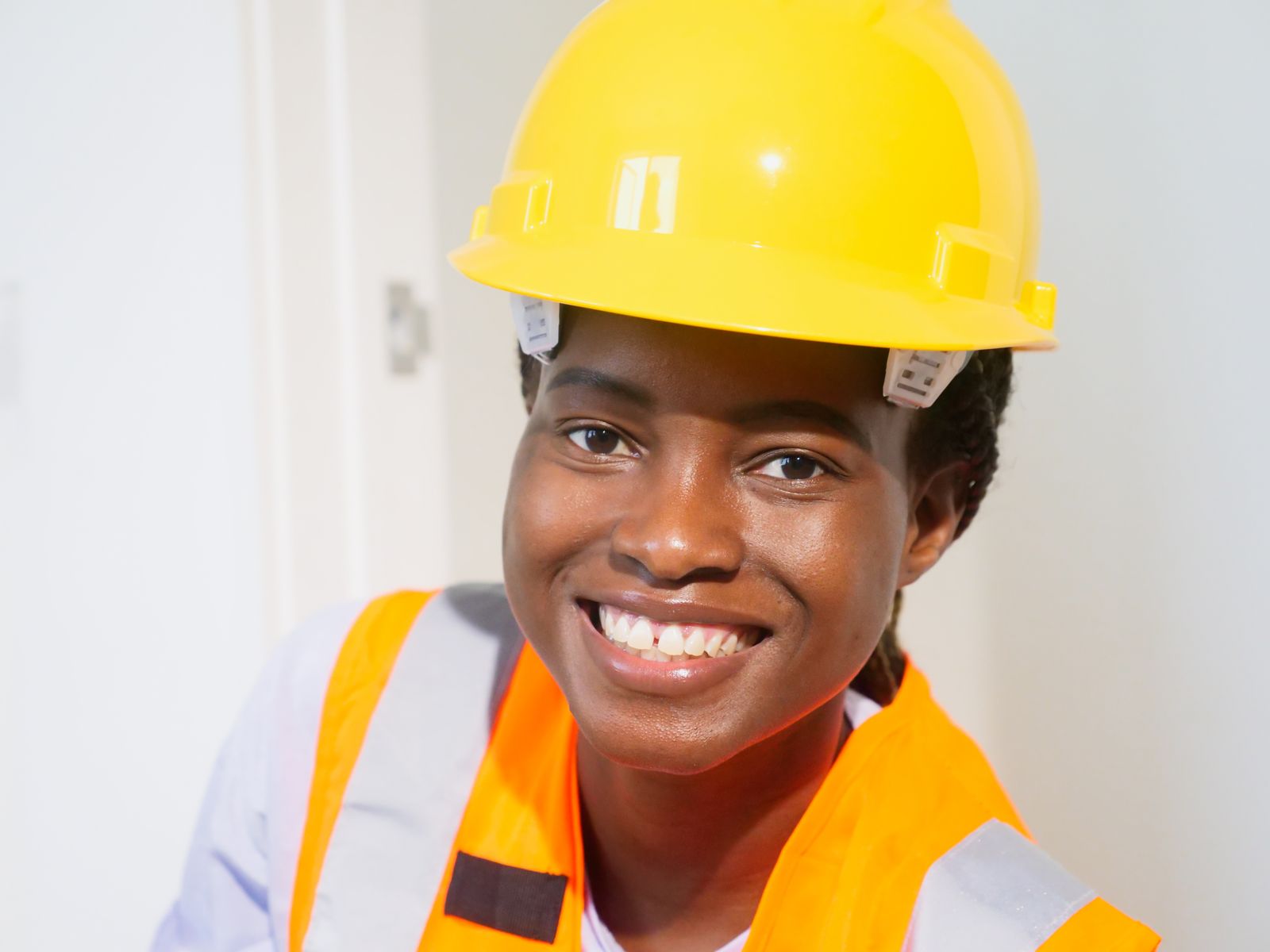 A young South African woman in a hard hat and safety vest, smiling — representing youth skills and opportunity in the energy and water sectors